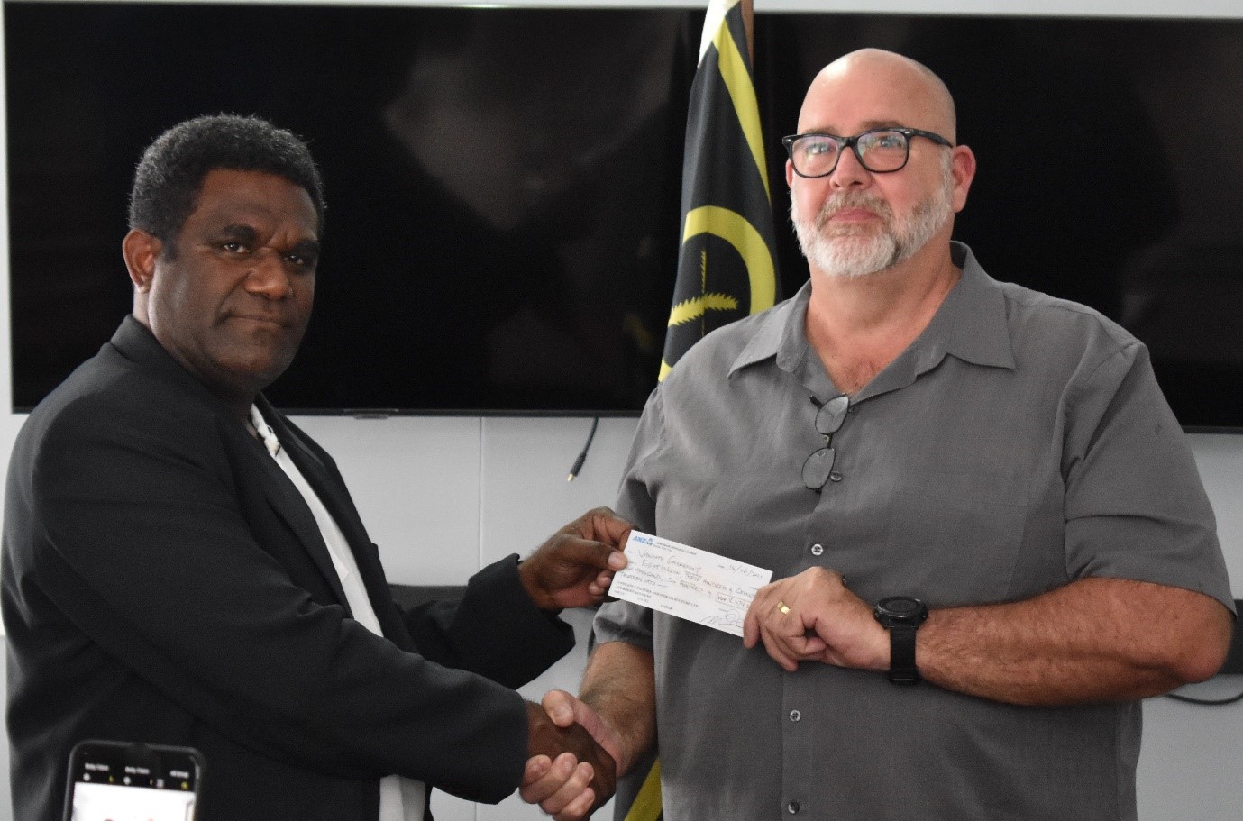 Minister of Finance, Hon Johnny Koanapo Raso (l) receives cheque from VUI’s General Manager, Peter Allen (r). Photo: Department of Energy